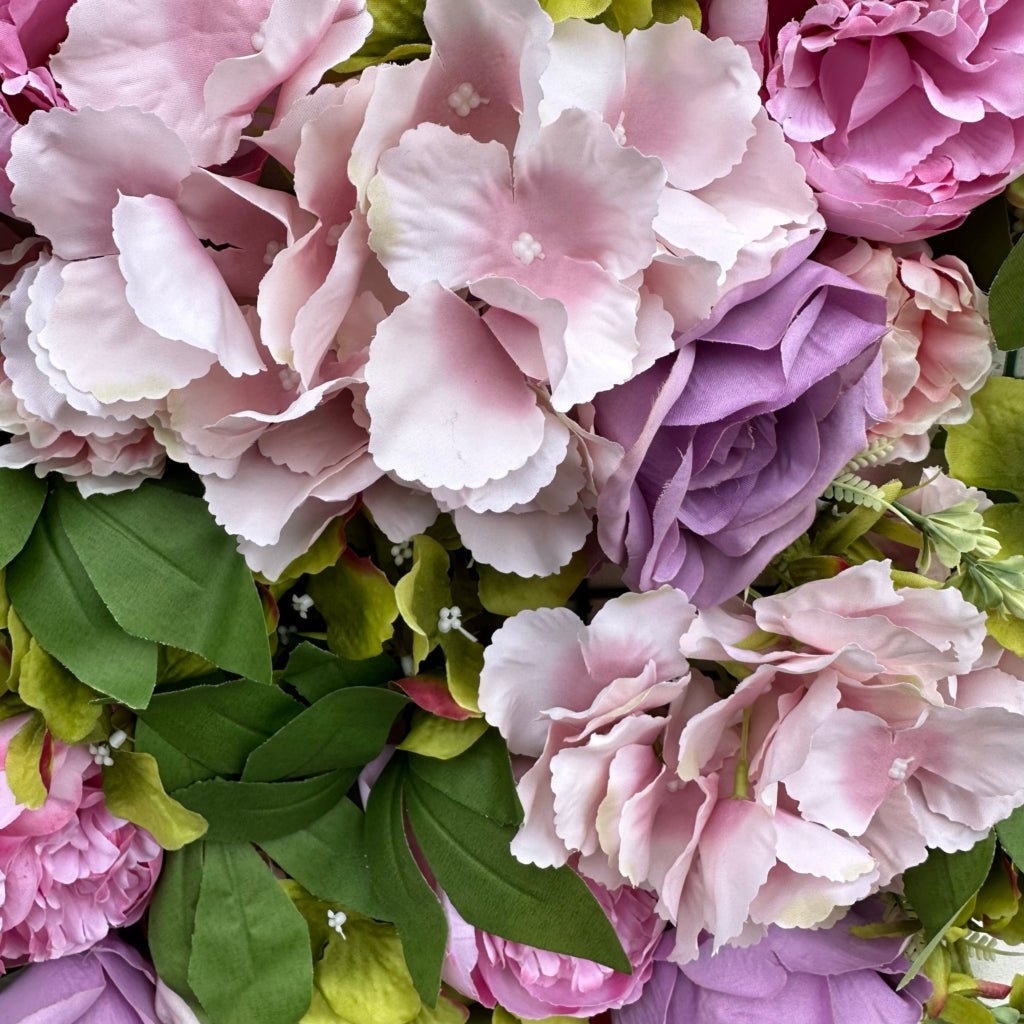 Floral mat closeup with pink and lilac peonies, roses, hydrangea petals, and green leaves