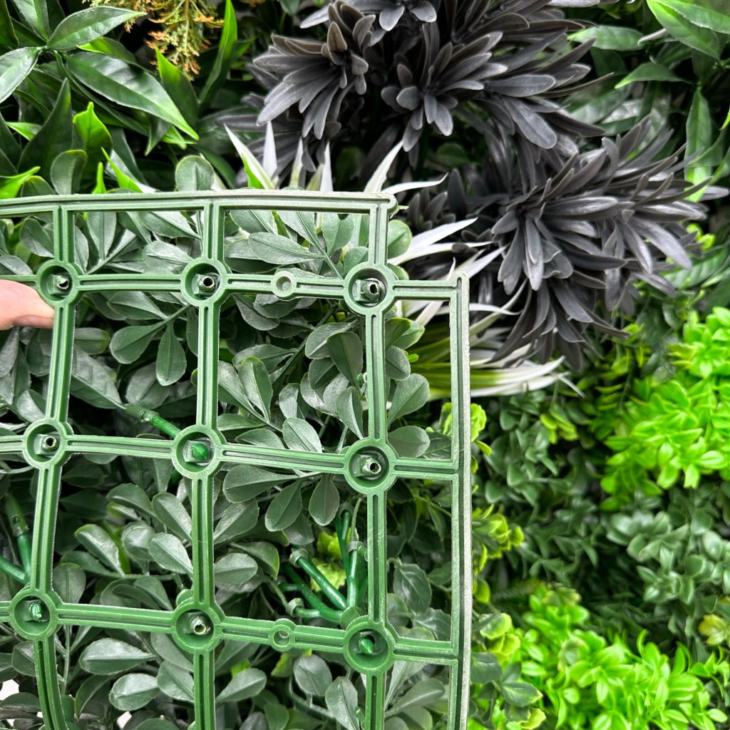 Artificial foliage wall panel closeup with green lattice backing and faux leaves