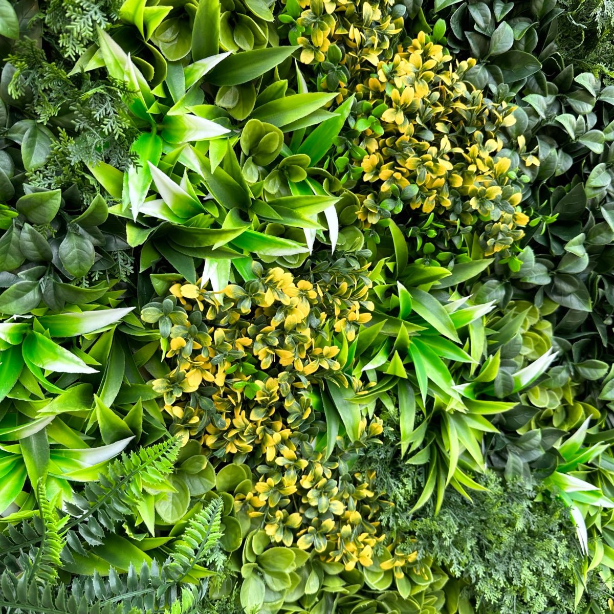 Artificial green wall panel close-up of fern fronds, yellow clusters, broad leaves