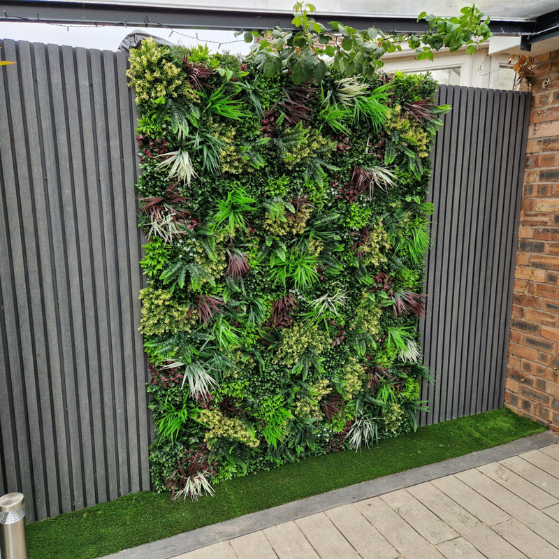 Artificial green wall panel with variegated greens of ivy, ferns, palm heads, grasses & yellow tipped privets 100x100 cm