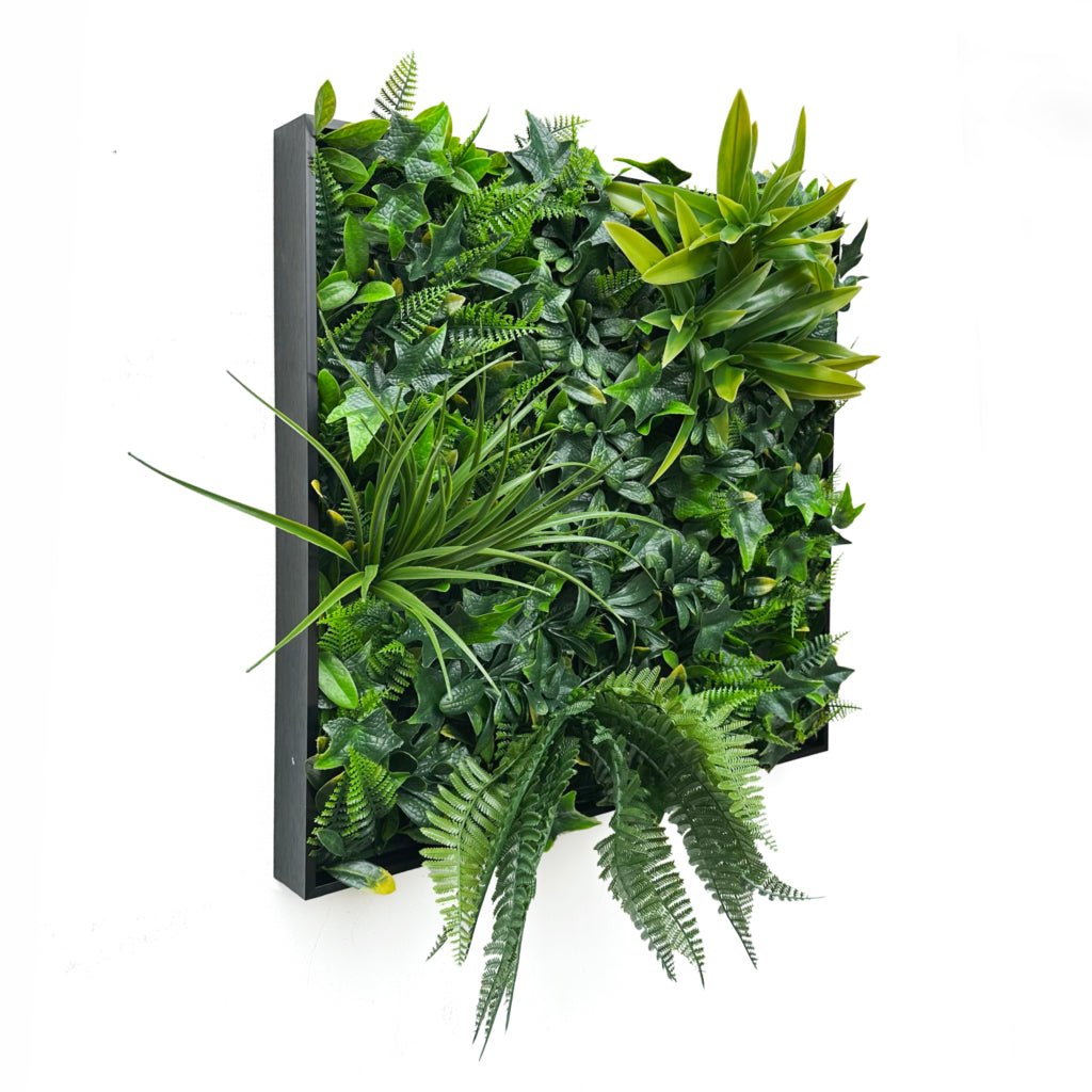 Artificial foliage wall art panel with dense green leaves on black frame and backing