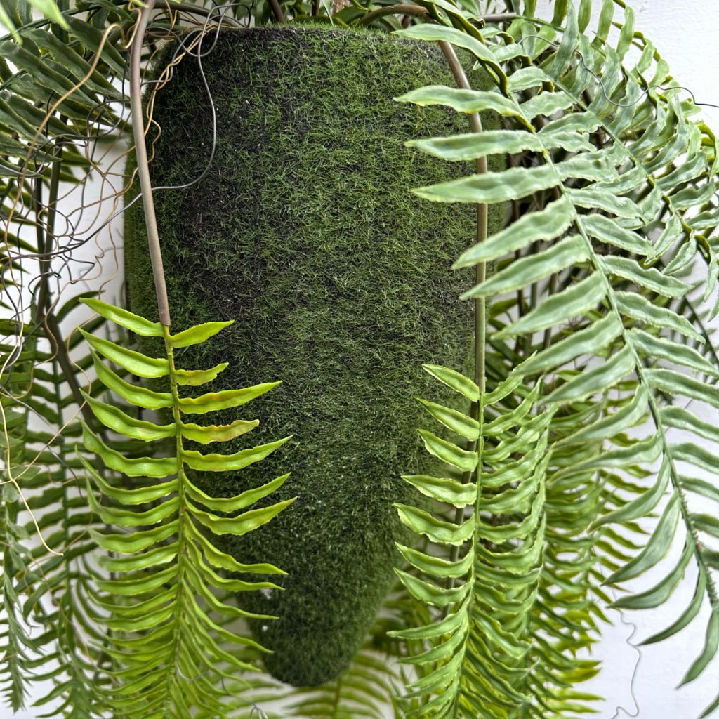 Artificial kokedama moss backdrop with bright green trailing fern fronds