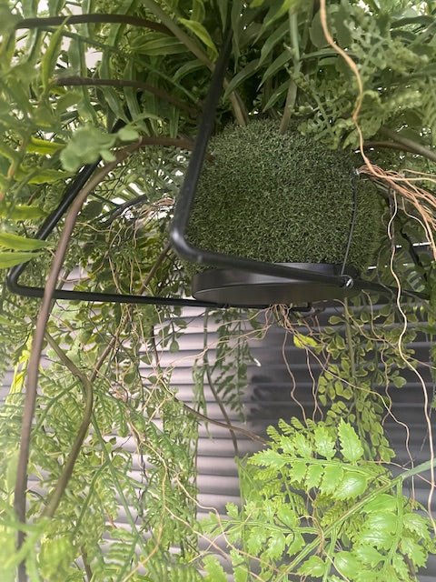 Artificial kokedama detail with green moss ball and black metal hanging frame
