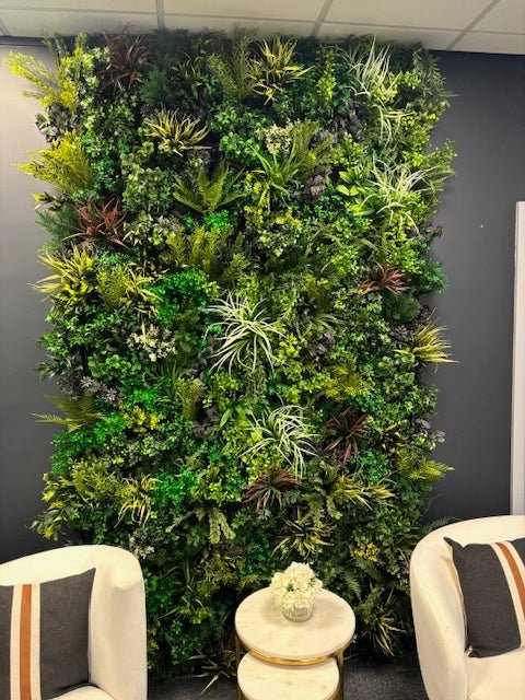 Large indoor artificial plant wall with varied green textures and occasional purple-speckled leaves