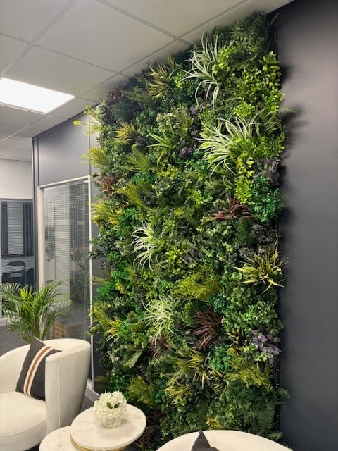 Tall artificial plant wall with dense green foliage and small purple highlights