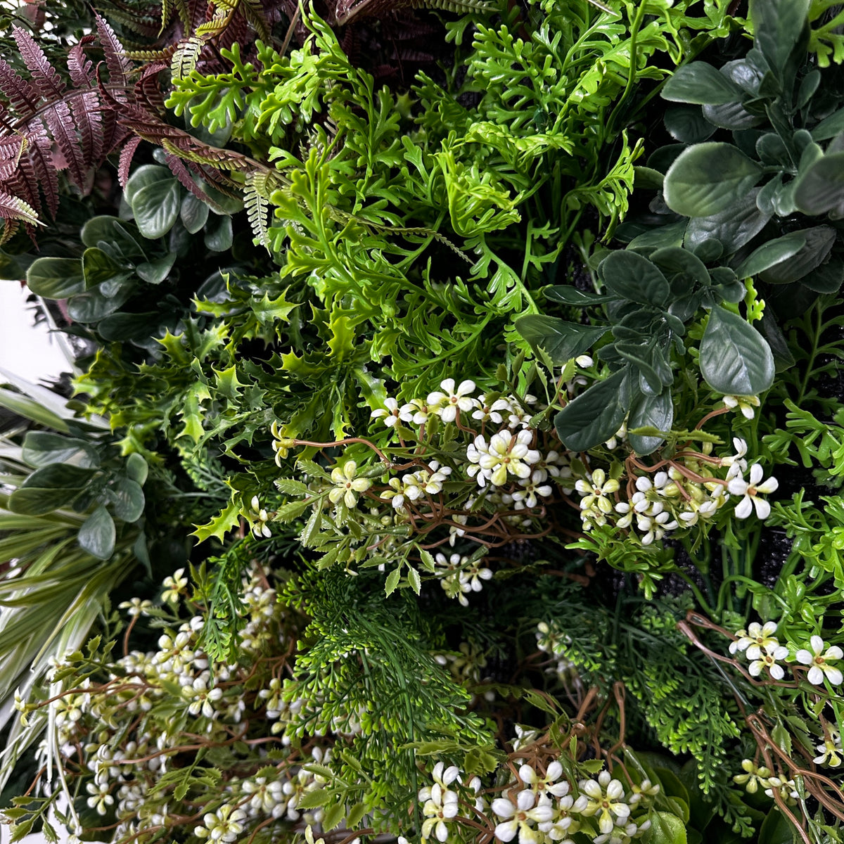 Artificial plant wall panel close-up of bright green foliage with white flower clusters