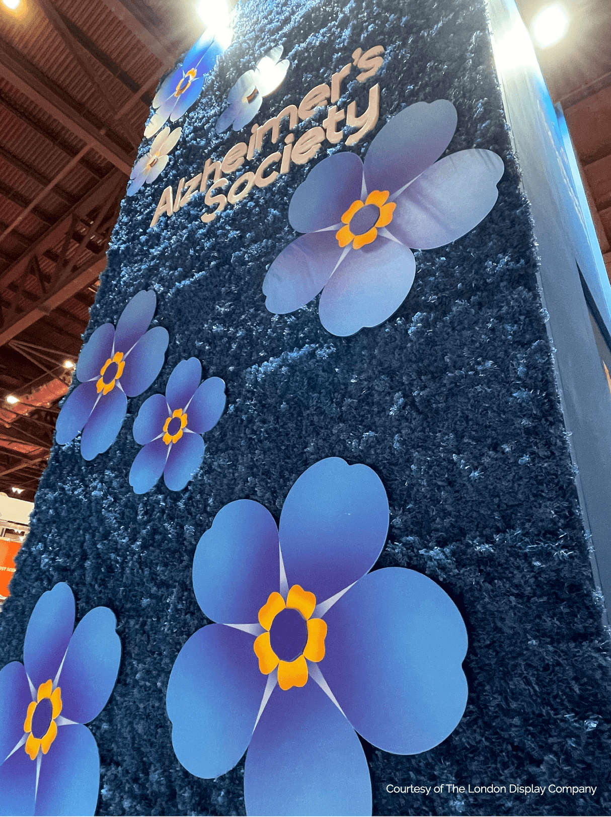 Blue moss panel with oversized paper flowers and 'Alzheimer's Society' lettering