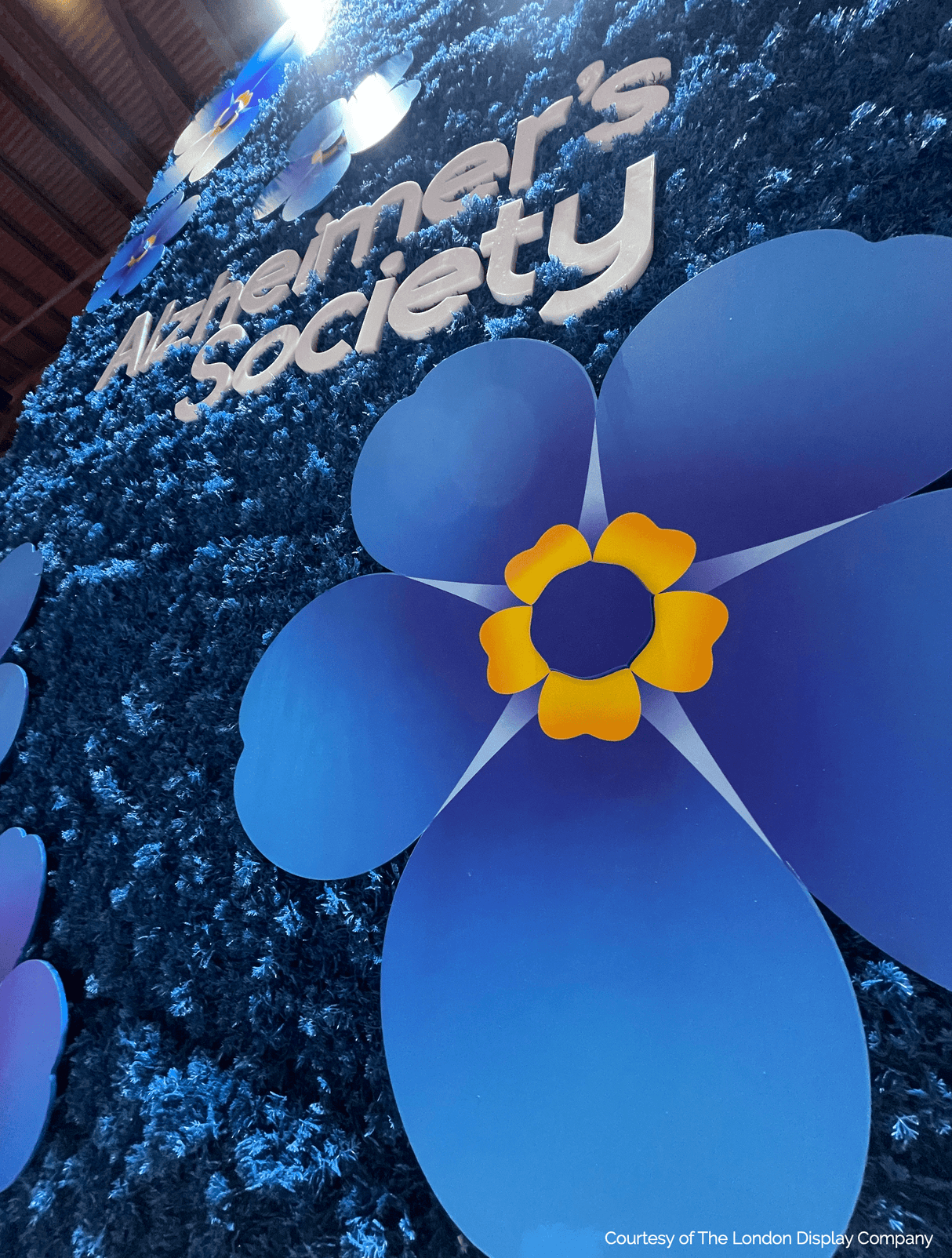 Blue moss panel with large paper flowers and 'Alzheimer's Society' lettering