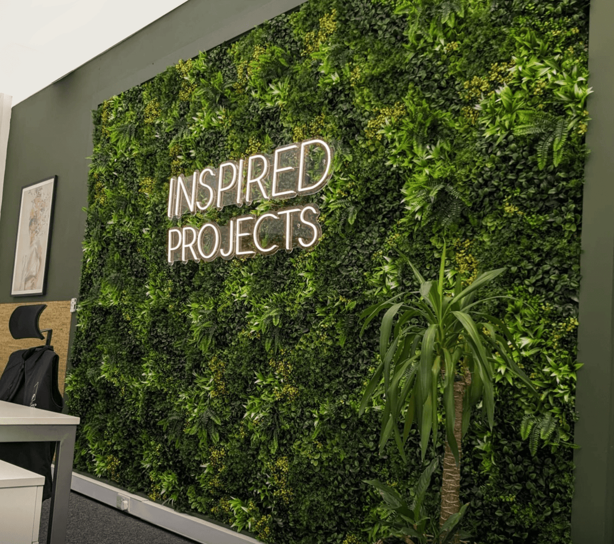 Artificial green wall panel with dense green foliage and fern accents on interior wall