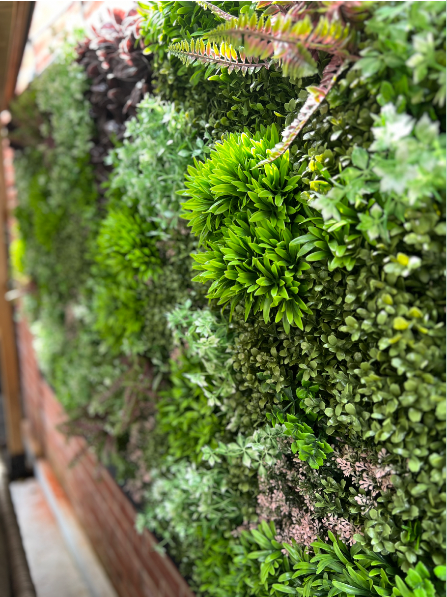 Artificial wall panel corner close-up with bright green clusters and white-tipped plants
