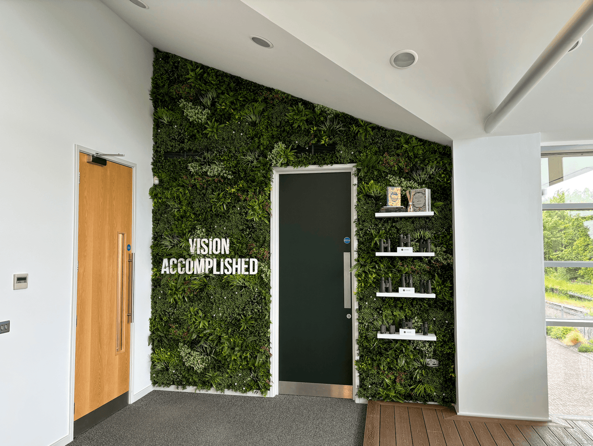 Artificial green wall panel backdrop with textured foliage around door and shelving