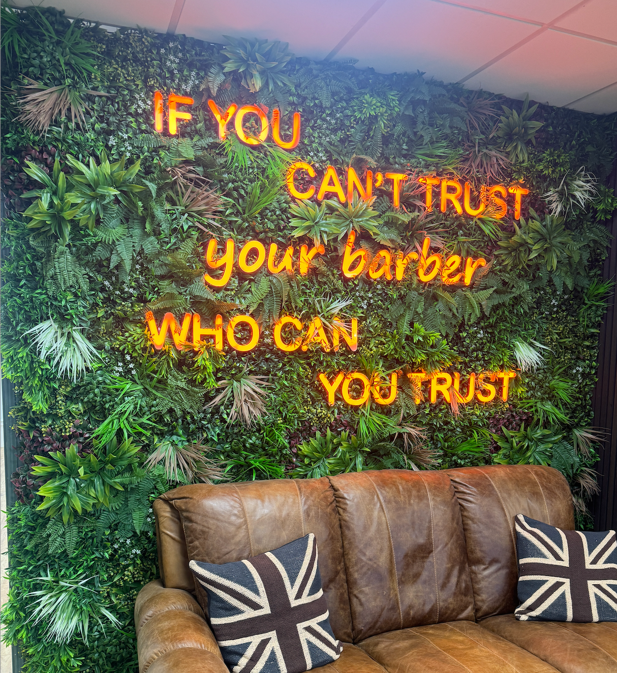Artificial green wall panel with thick layered foliage in green tones, with occasional white blooms