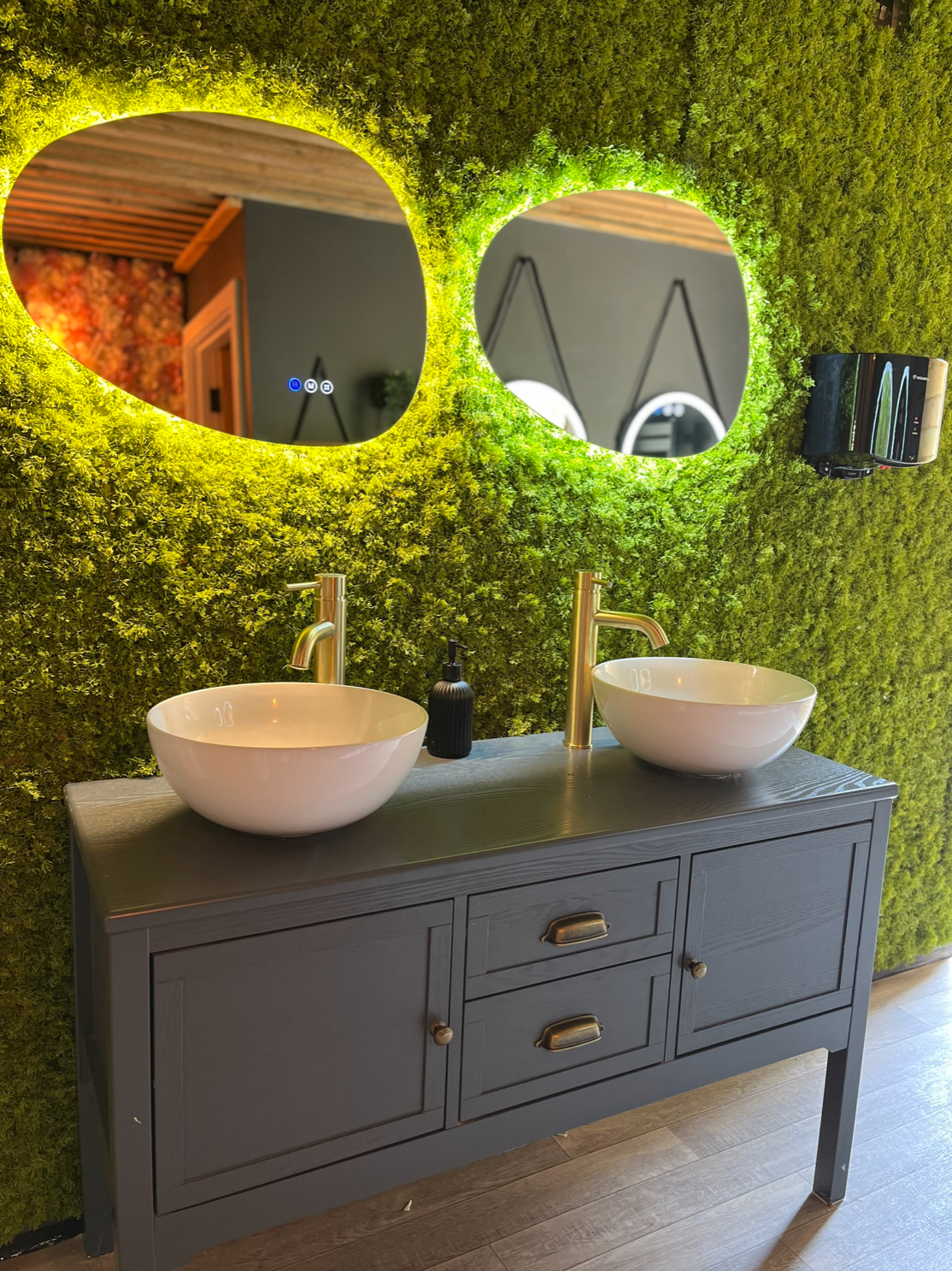 Artificial moss panel wall with green textured surface around oval mirror cutouts