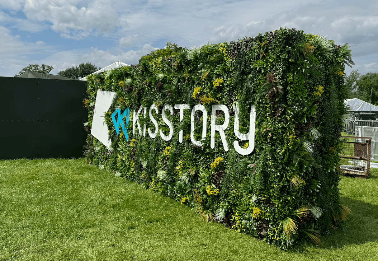 Artificial green wall panel with dense variegated foliage and white cutout lettering