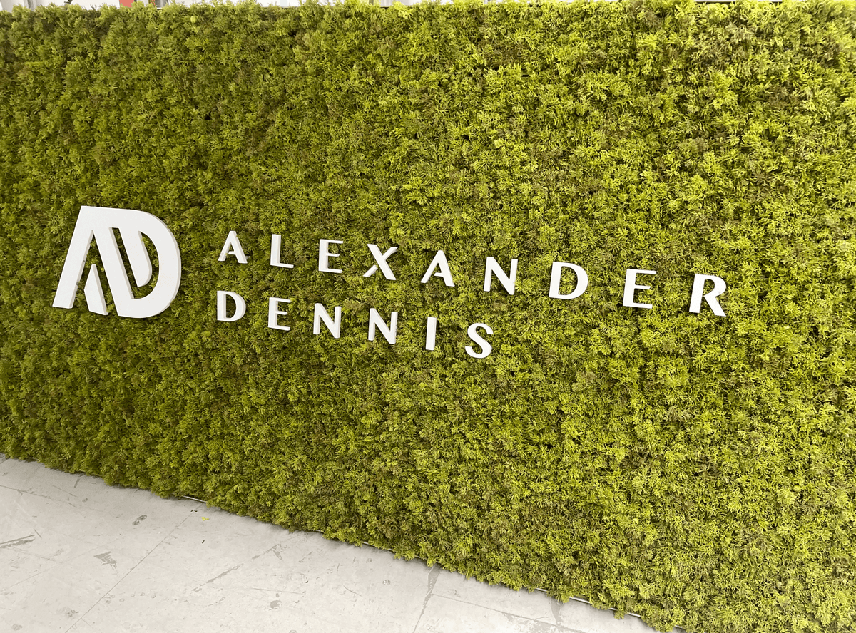 Artificial moss panel wall with green texture and white letters reading ALEXANDER DENNIS