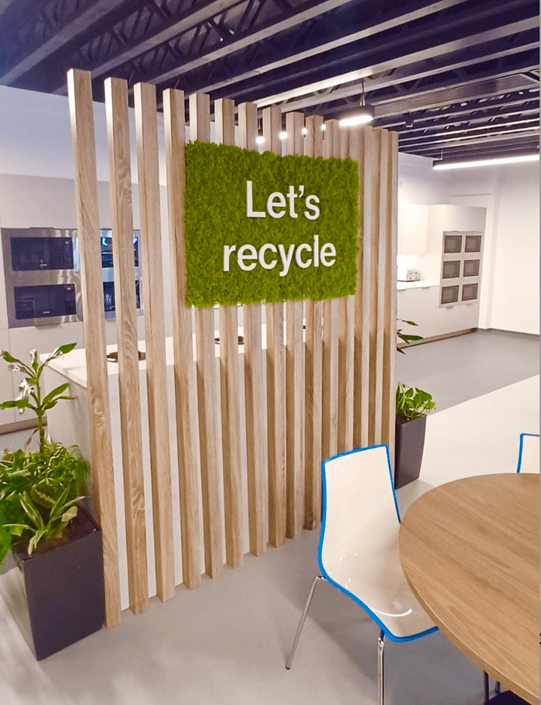 Artificial moss panel wall section with green texture behind a partition and sign
