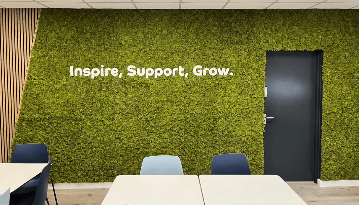 Artificial moss panel wall with green texture and white text: Inspire, Support, Grow.
