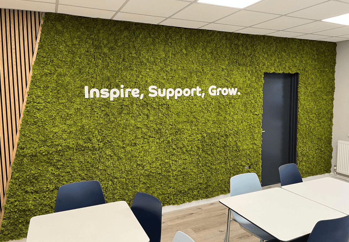Artificial moss panel wall with green texture and white text: Inspire, Support, Grow.