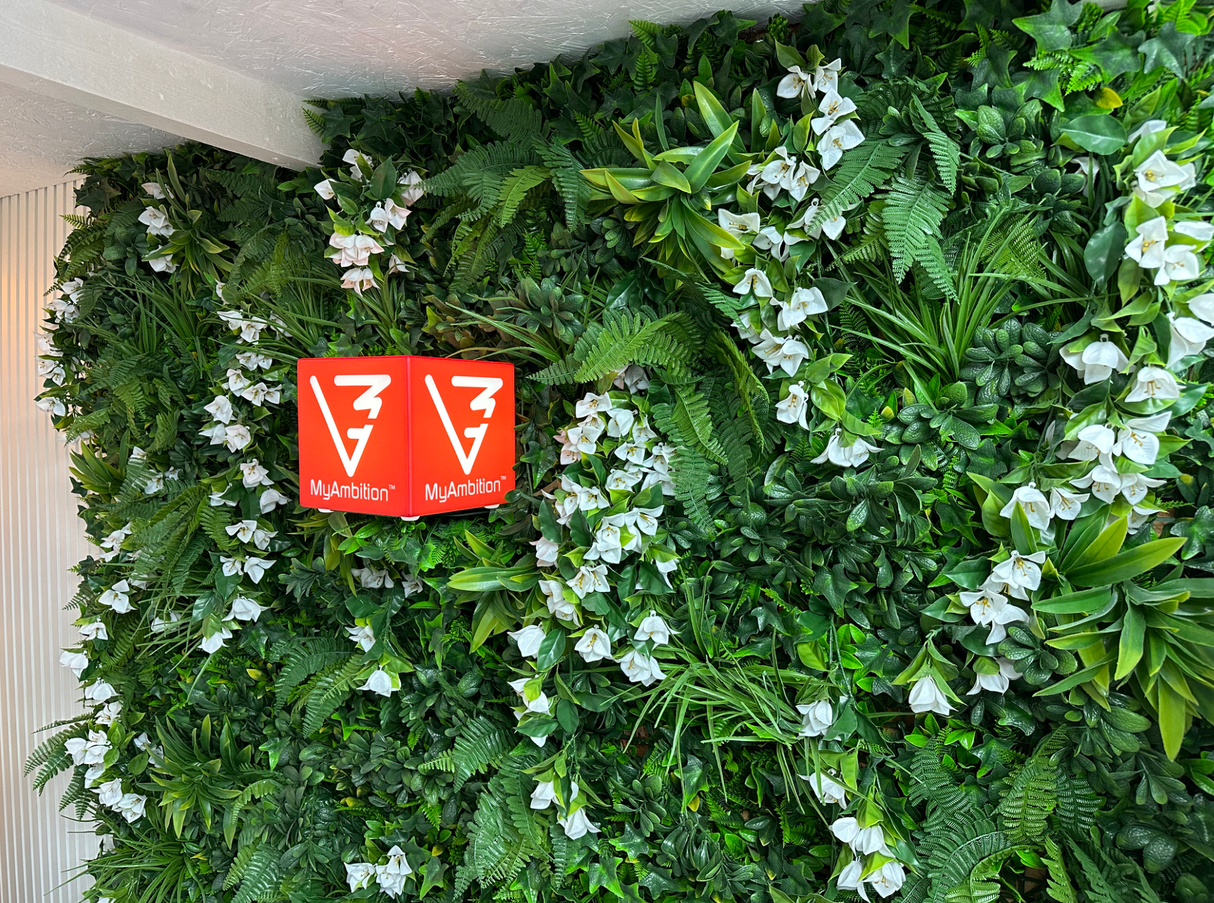 Artificial foliage wall panel corner view with white flowers and MyAmbition red signage