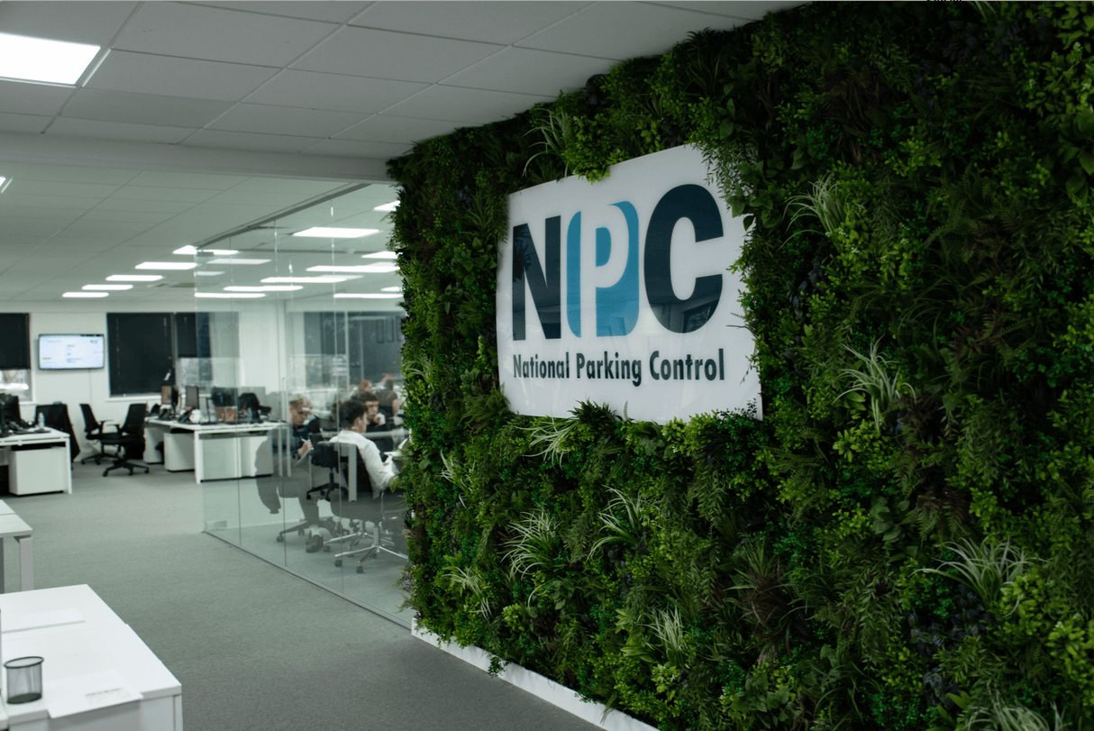 Artificial foliage wall panel with a white NPC National Parking Control sign