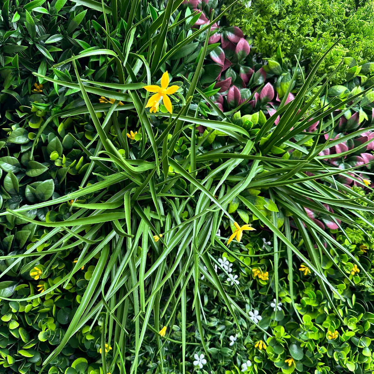 Artificial green foliage wall panel with yellow, white and dark pink flowers