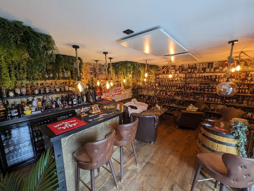 Artificial hanging green foliage wall covering with cascading vines over a bar area