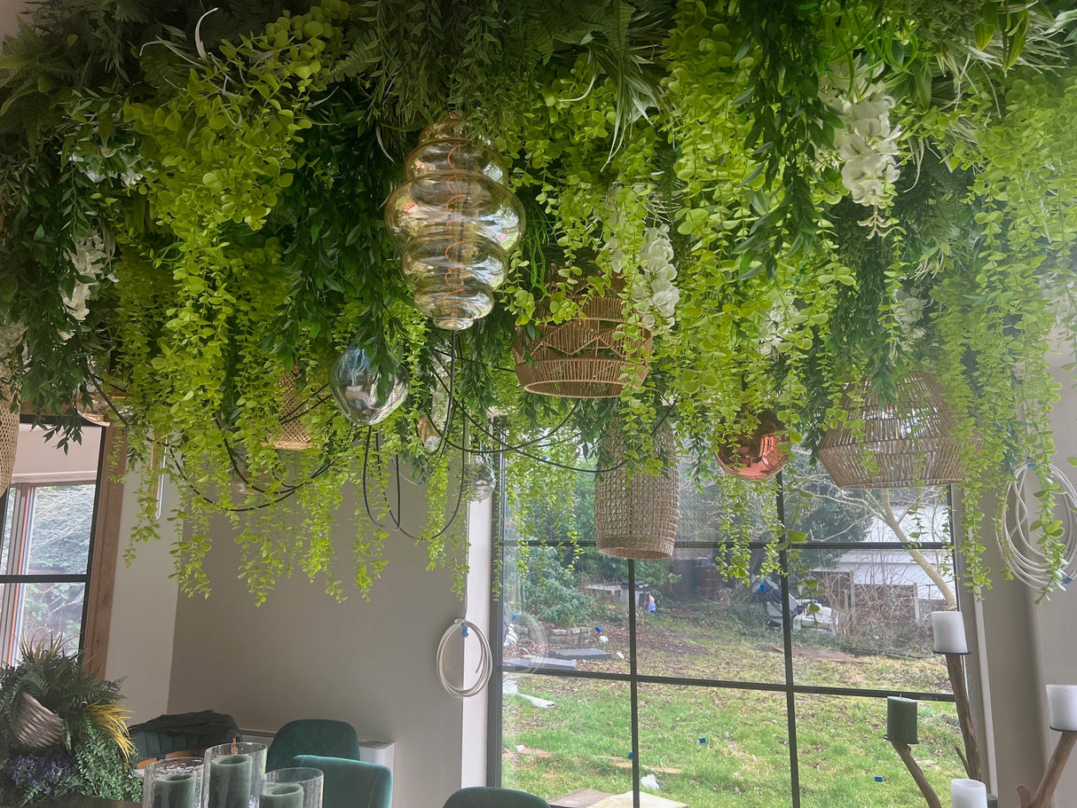 Artificial hanging green foliage panel with dense trailing leaves near windows