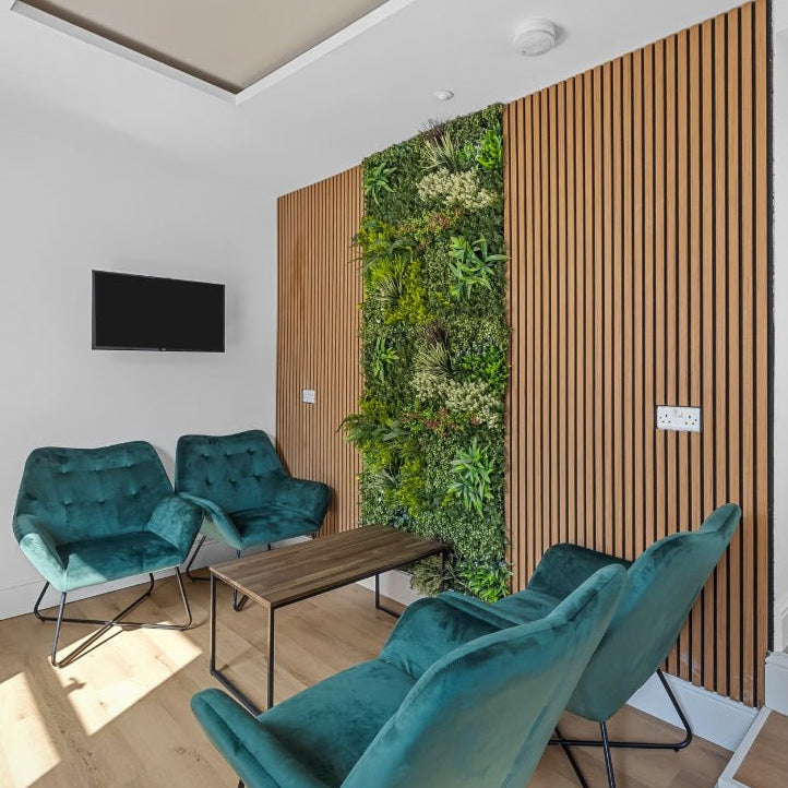 Artificial green foliage wall panel, dense mixed-leaf texture on a square wall section.
