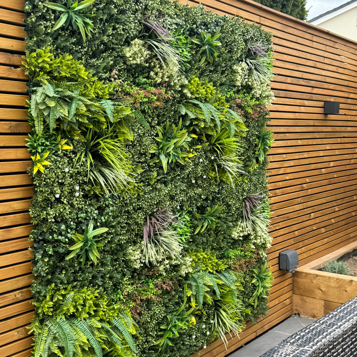 Artificial green foliage wall panel with mixed yellow, red, white leaves