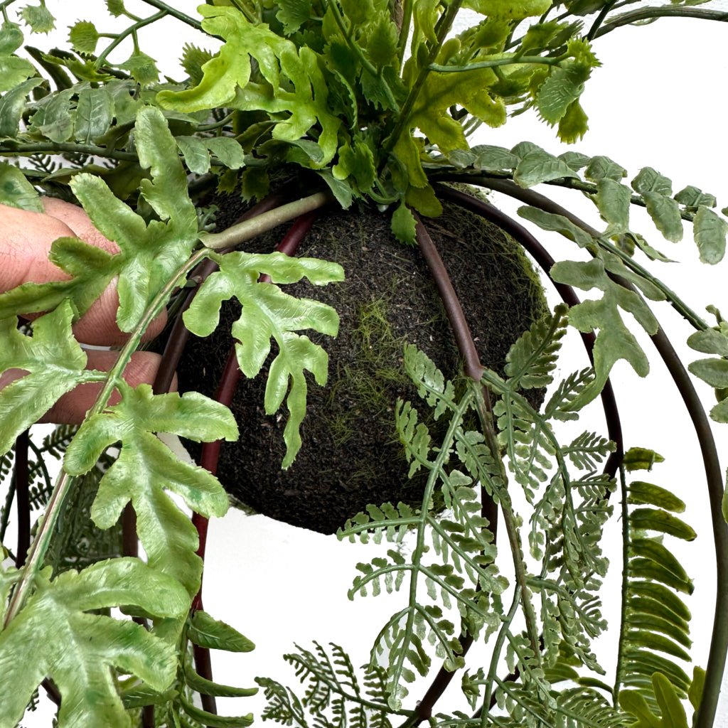 Artificial trailing fern kokedama with dark moss ball and green leaves, hanging plant