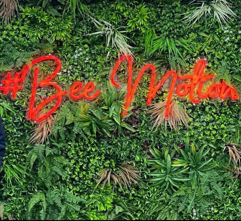 Artificial green foliage wall panel with red neon-style “#3 Bee” text