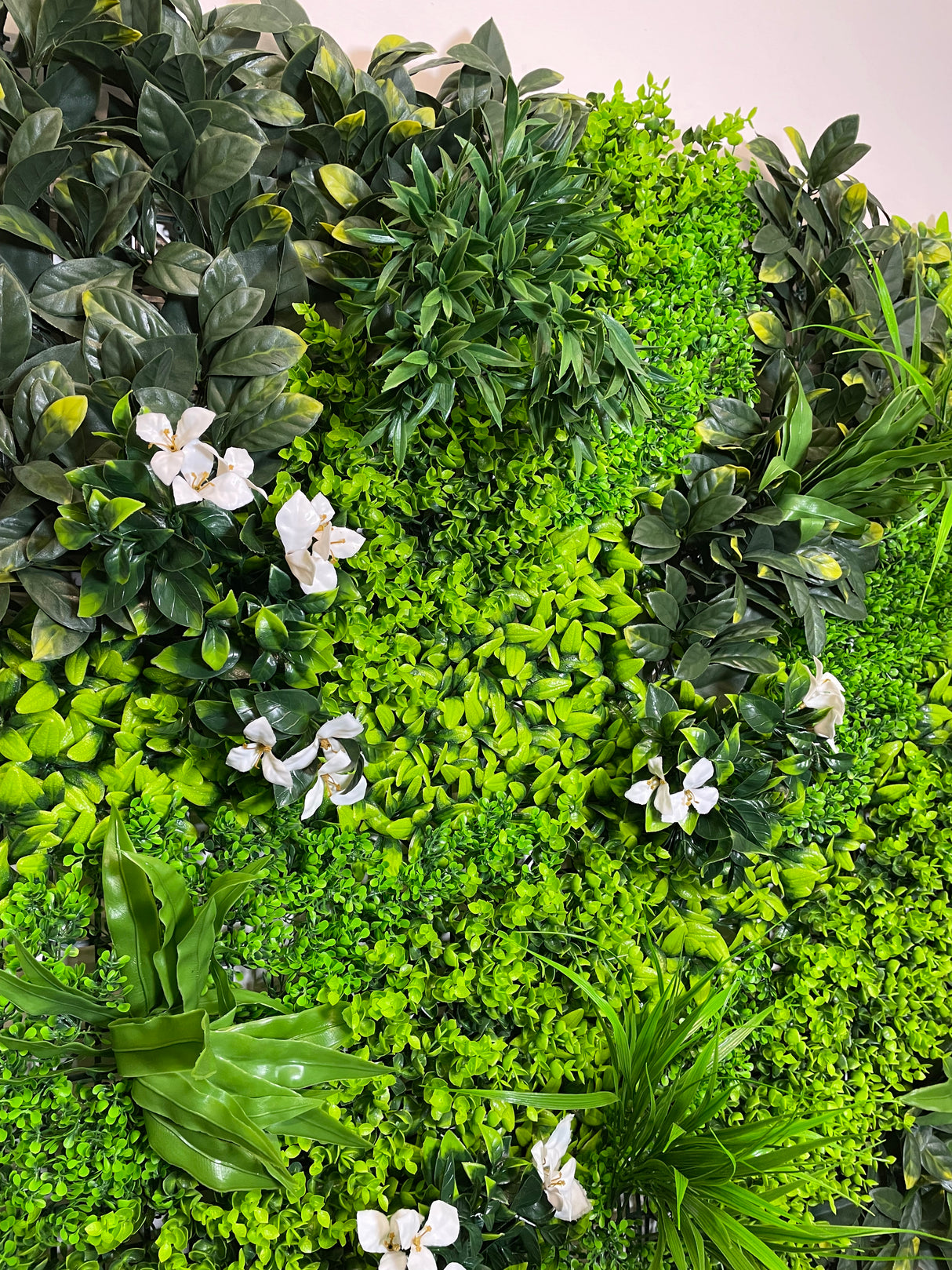 Artificial green wall panel with variegated green foliage palms grasses eucalyptus and white flowers 100x100 cm