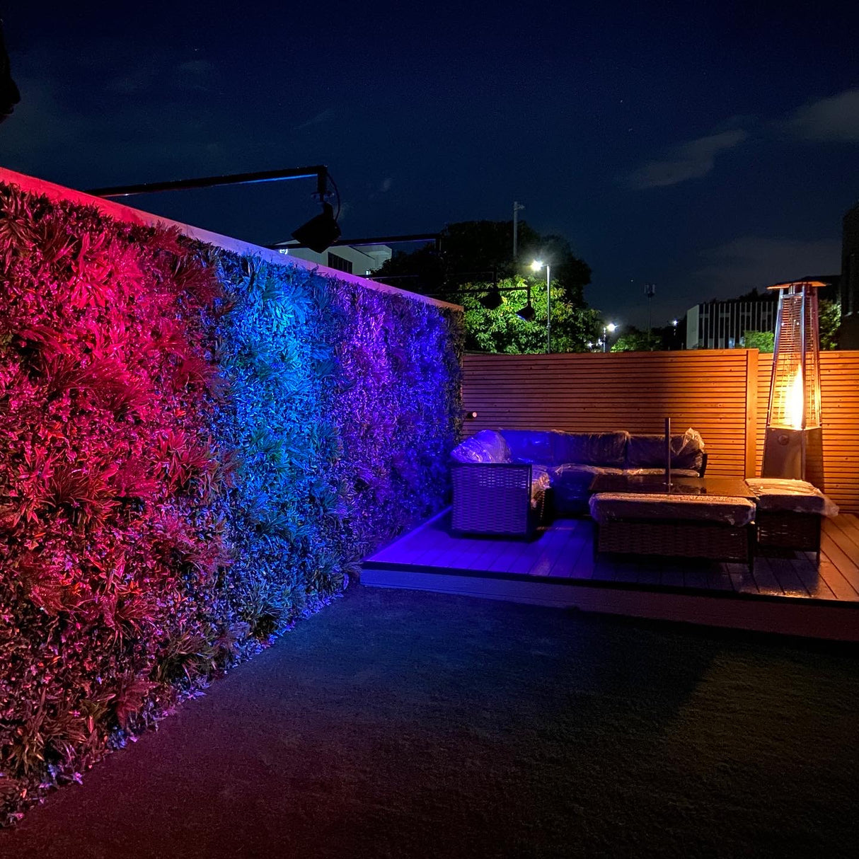 Artificial green wall panel with variegated greens of ivy, ferns, palm heads, grasses & small purple flowers  100x100 cm