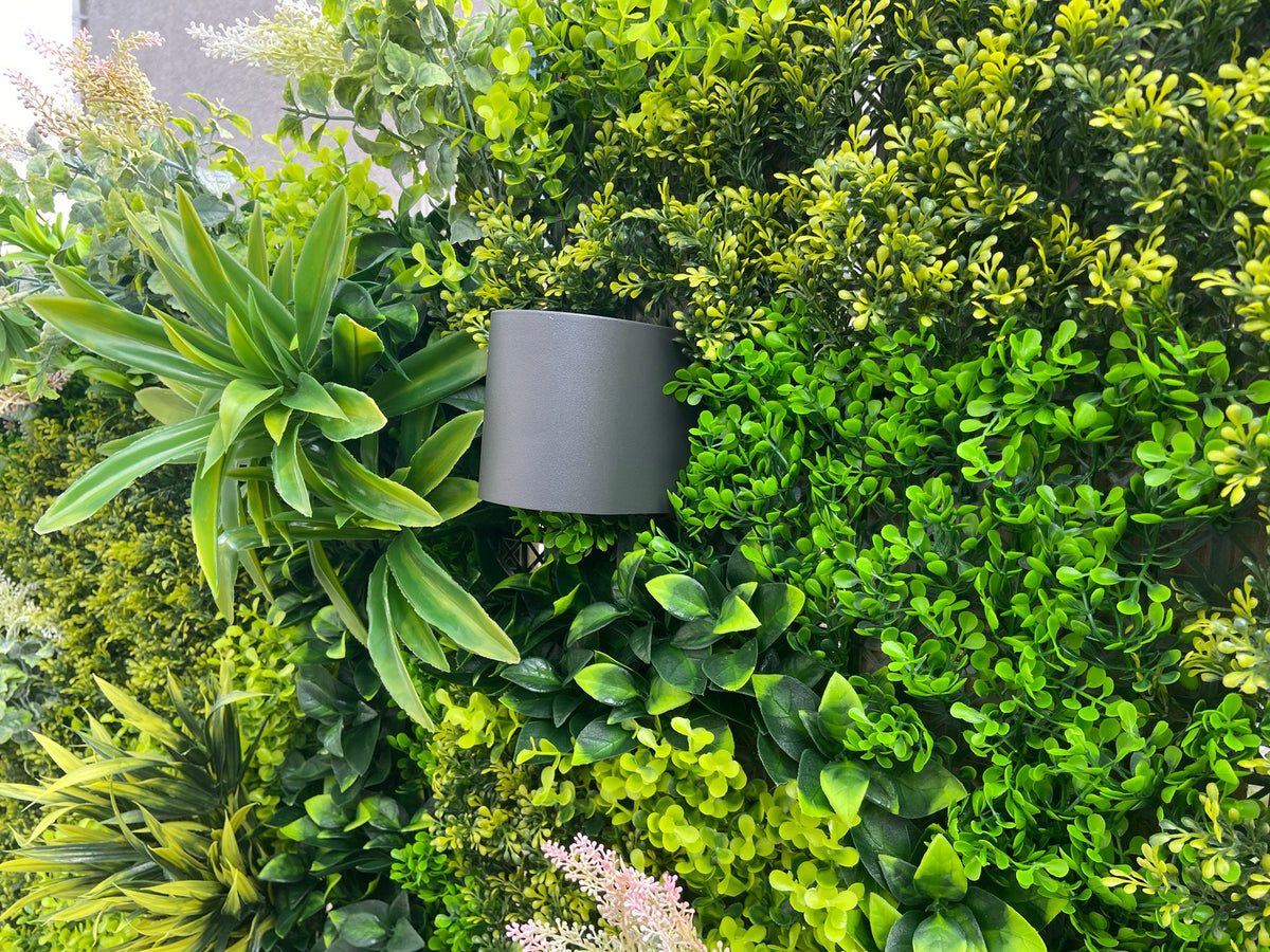 Artificial green foliage wall panel with dense leaf texture and pale white flower sprays