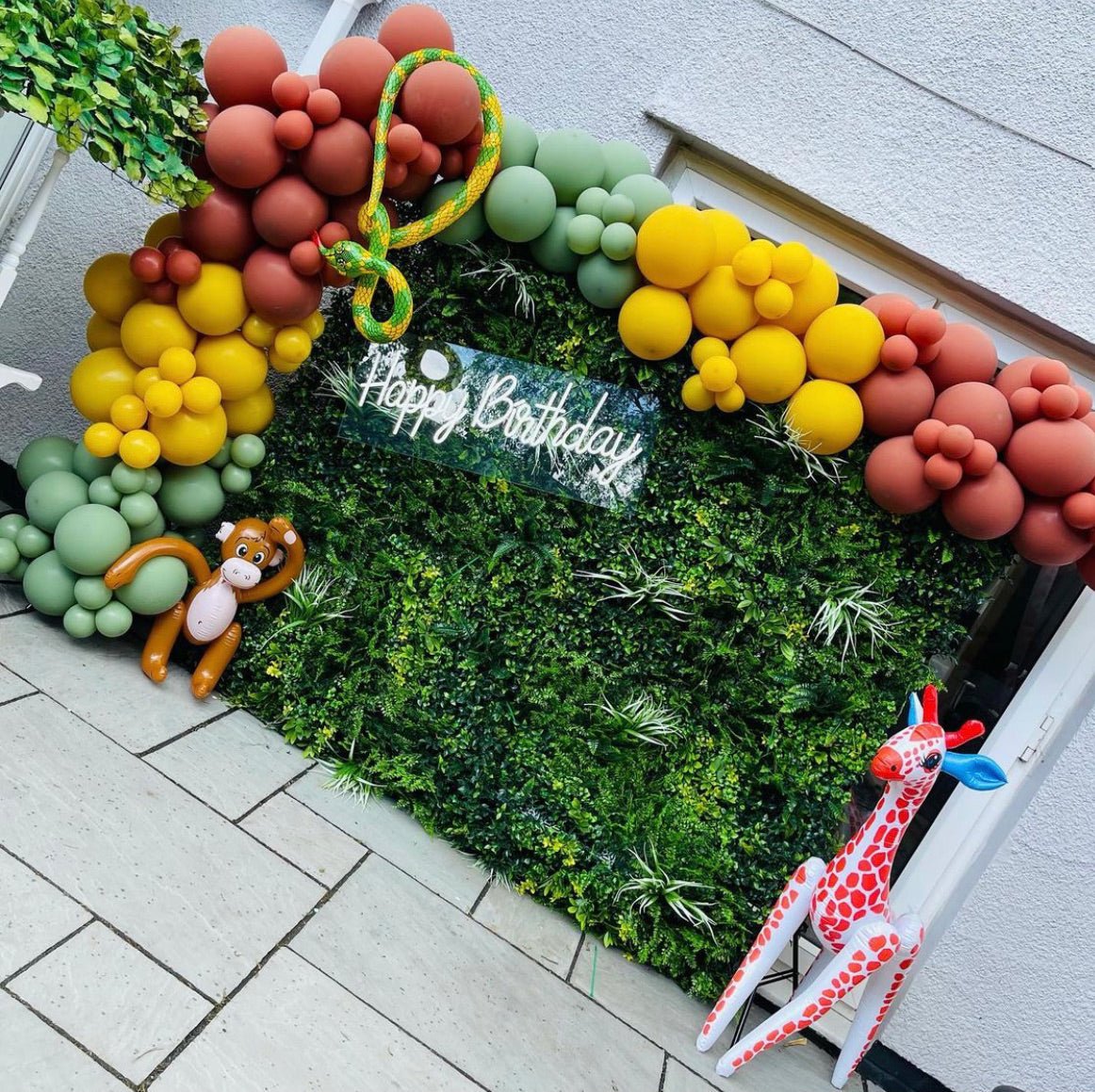 Artificial green wall panel decorated with faux foliage and yellow, white accents