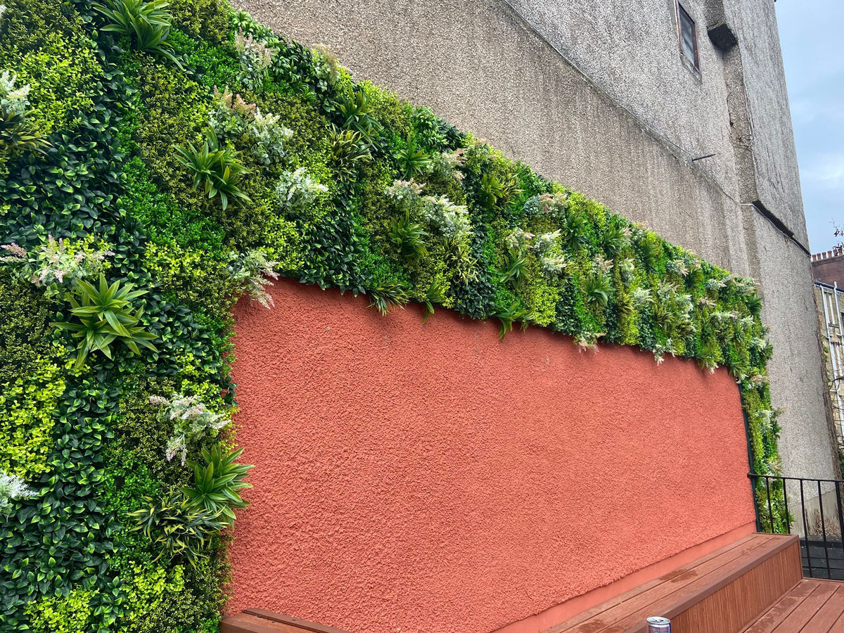 Artificial green wall panel with dense variegated foliage and white purple-pink blooms