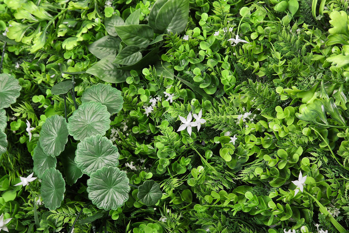 Artificial green plant wall panel with large leaf textures and scattered white star flowers