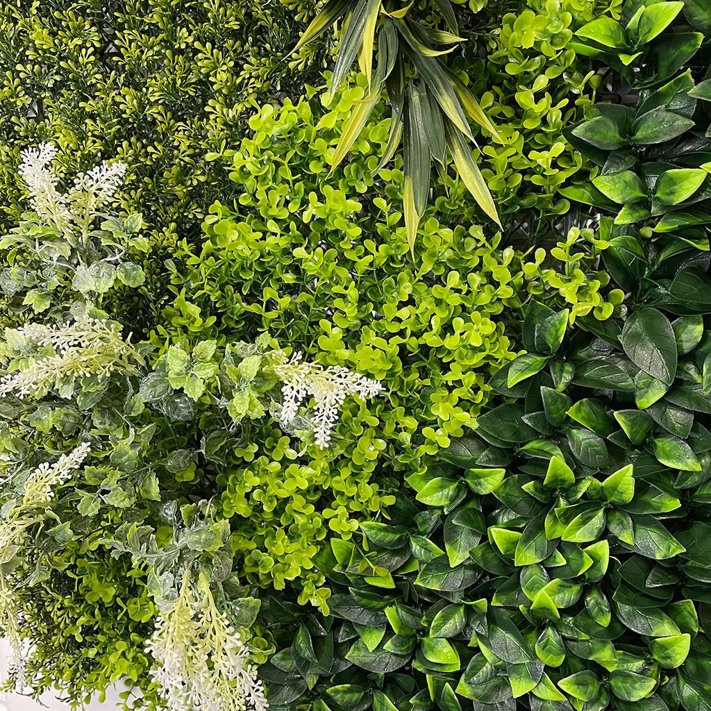 Artificial green foliage wall panel with white flowering heads and mixed palm leaves