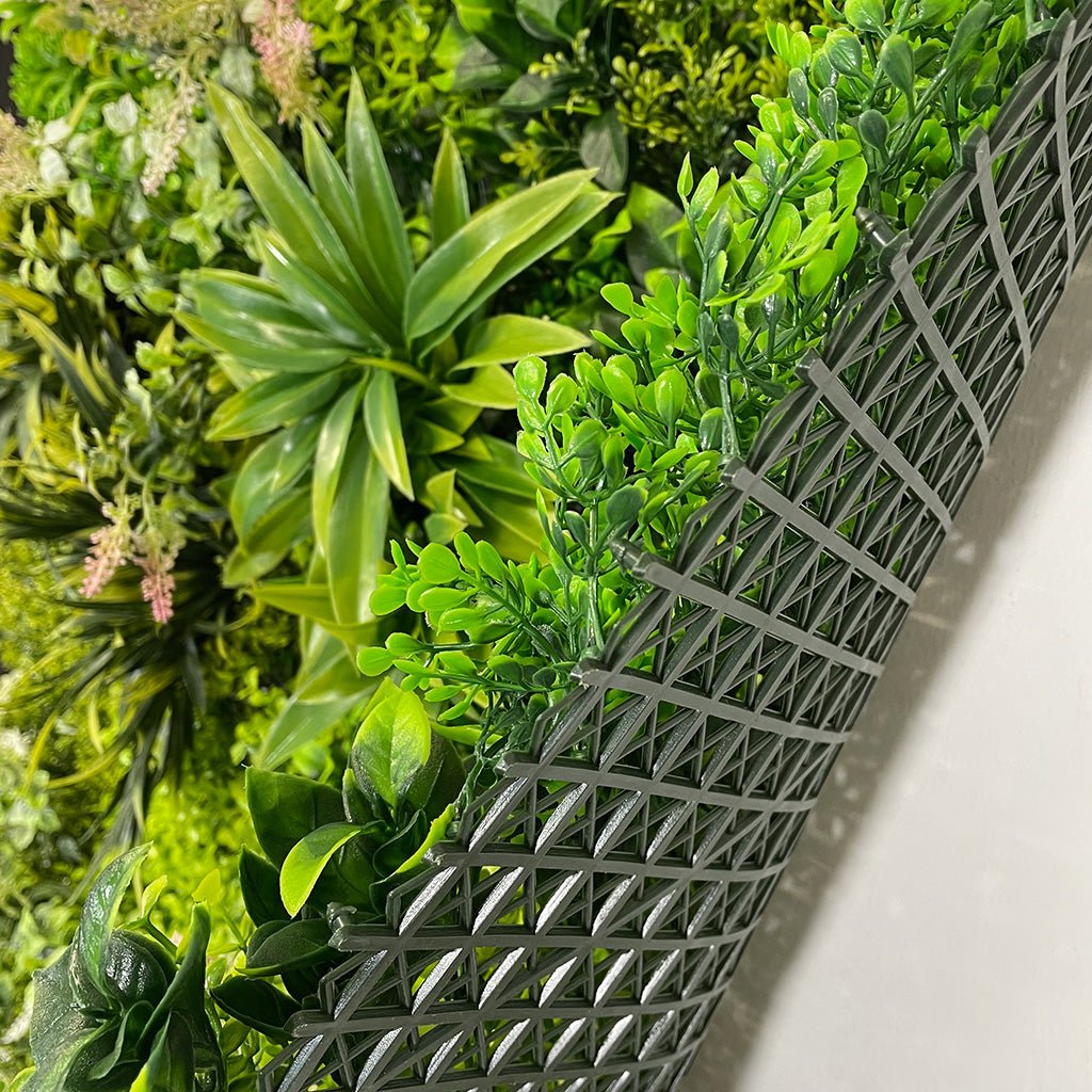 Artificial green foliage wall panel with dense leaves and pale flower clusters in corner