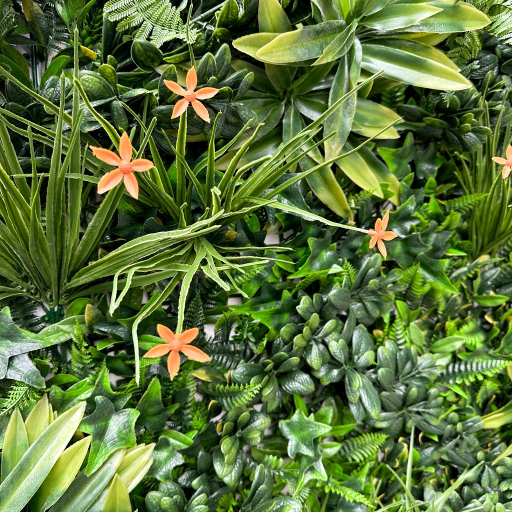 Artificial green wall panel close-up of green foliage with orange star flowers