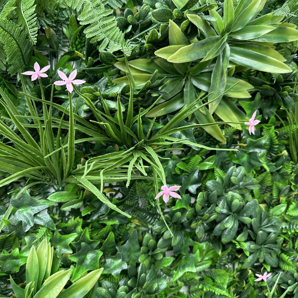 Artificial green wall panel with mixed foliage, variegated leaves and small pink flowers