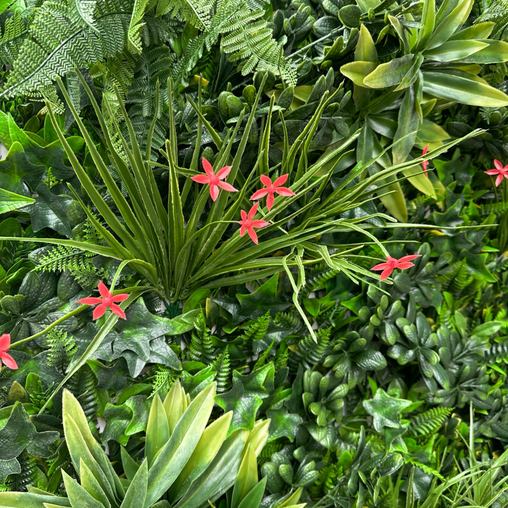 Artificial green wall panel with variegated greens of ivy, ferns, palm heads, grasses & small orange flowers 100x100 cm