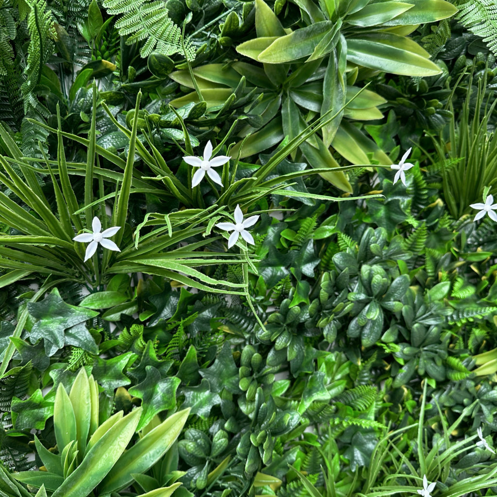 Artificial green wall panel with variegated greens of ivy, ferns, palm heads, grasses & small white flowers 100x100 cm
