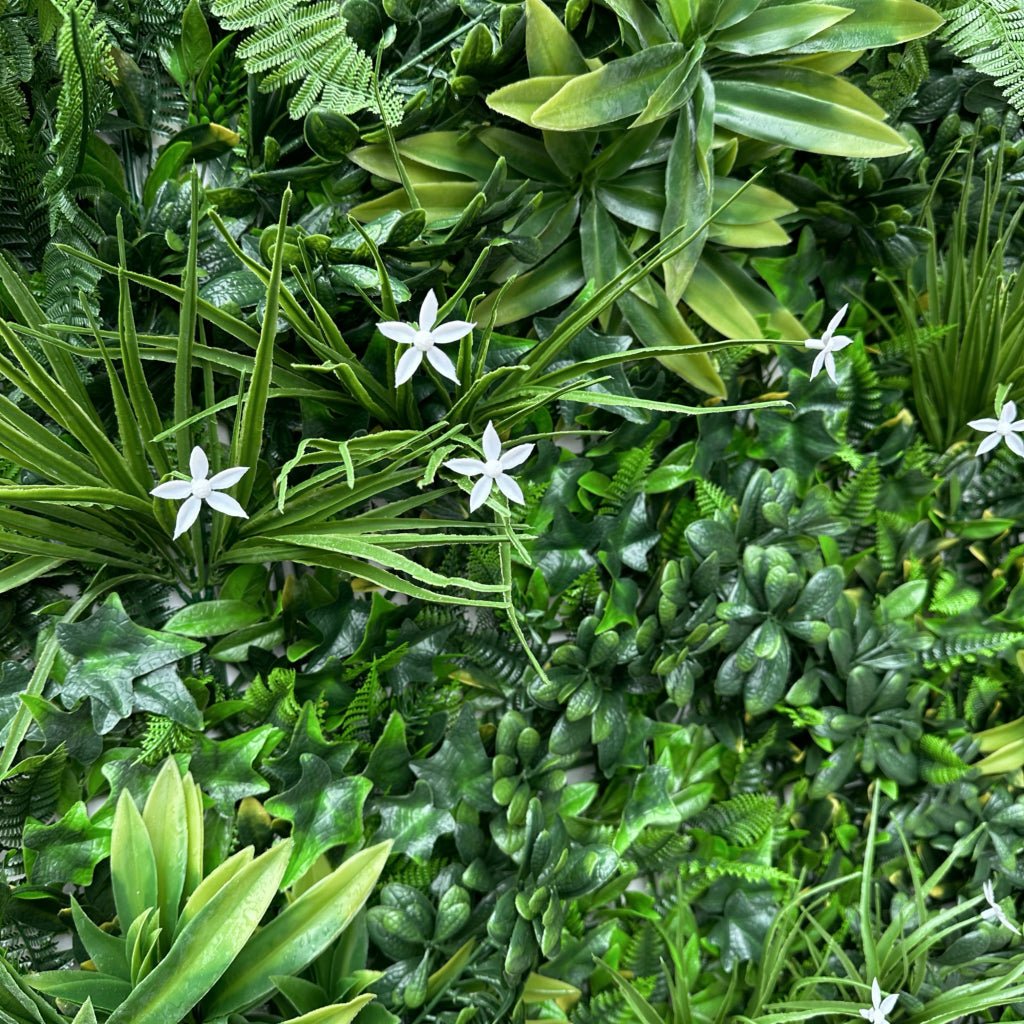 Artificial green wall panel close-up with grass blades, ferns and white star flowers