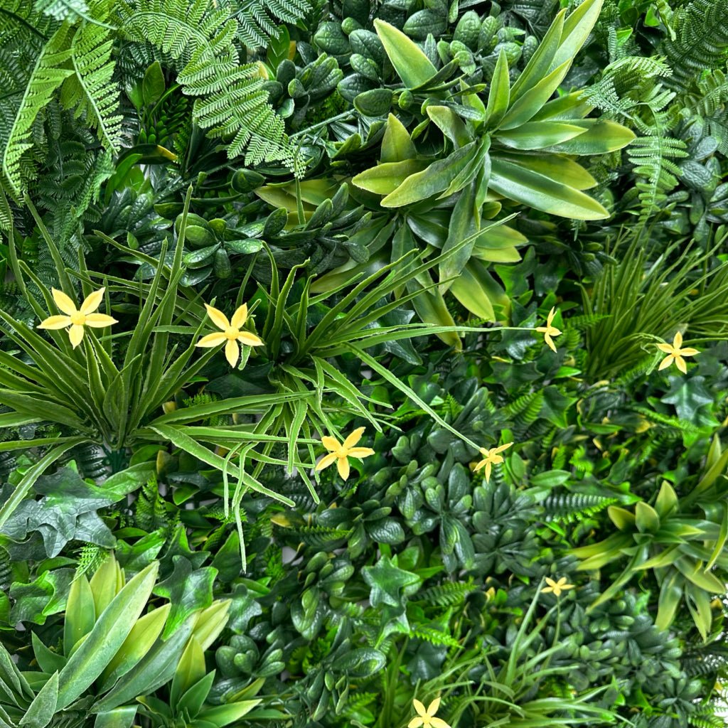 Artificial green wall panel close-up of varied green foliage with small yellow blossoms