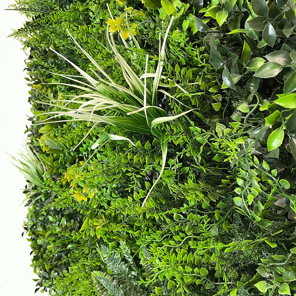 Artificial green wall panel with dense faux leaves, ferns and grasses in mixed green