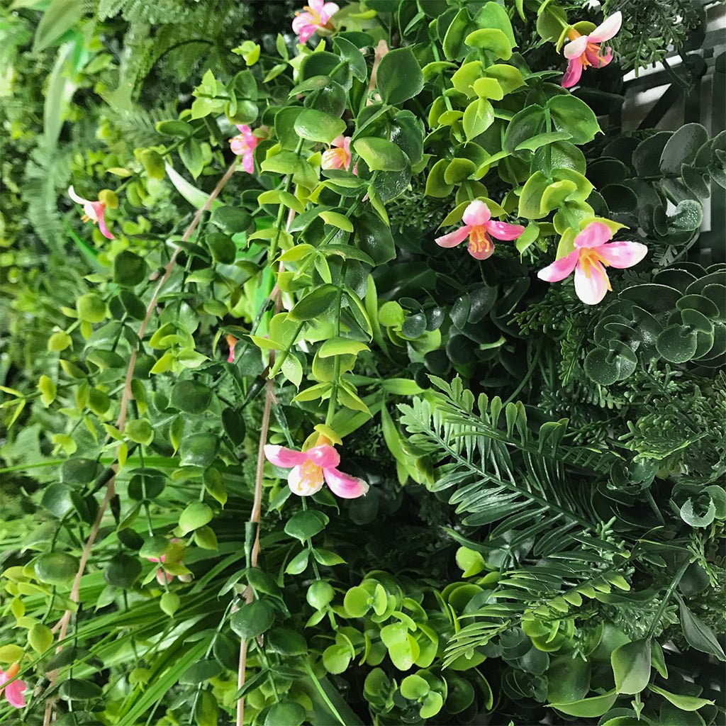 Artificial green foliage wall panel detail with pink orchid-like flowers and leaves