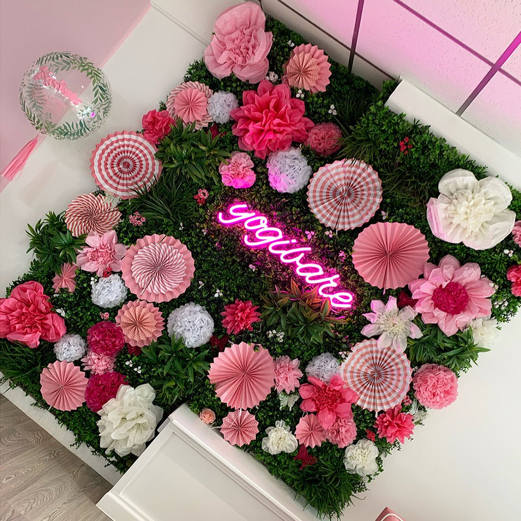 Artificial green wall panel with pink and white paper flower decorations