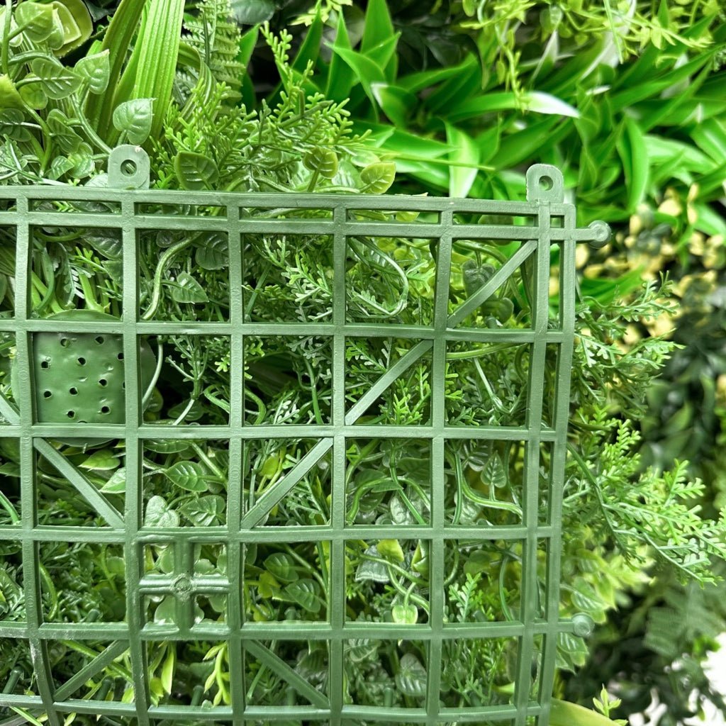 Artificial foliage wall panel with green grid backing and dense leaf texture behind