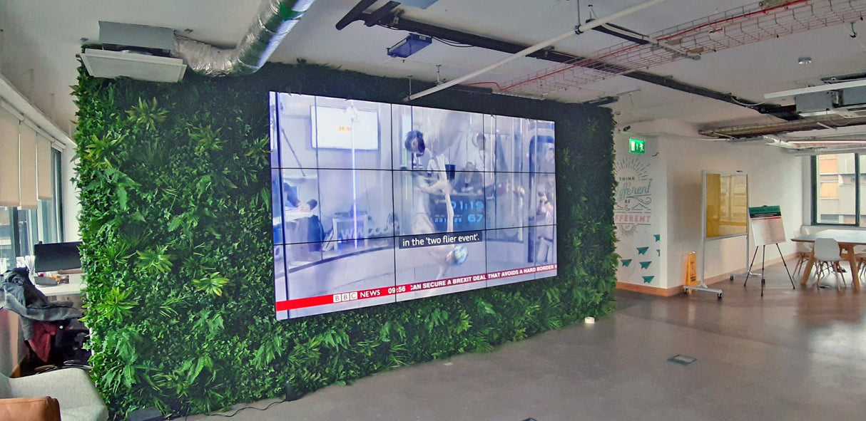 Artificial green wall panel covering a large wall section with layered faux foliage